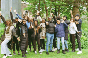 Group of smiling young people with their hands held in the air